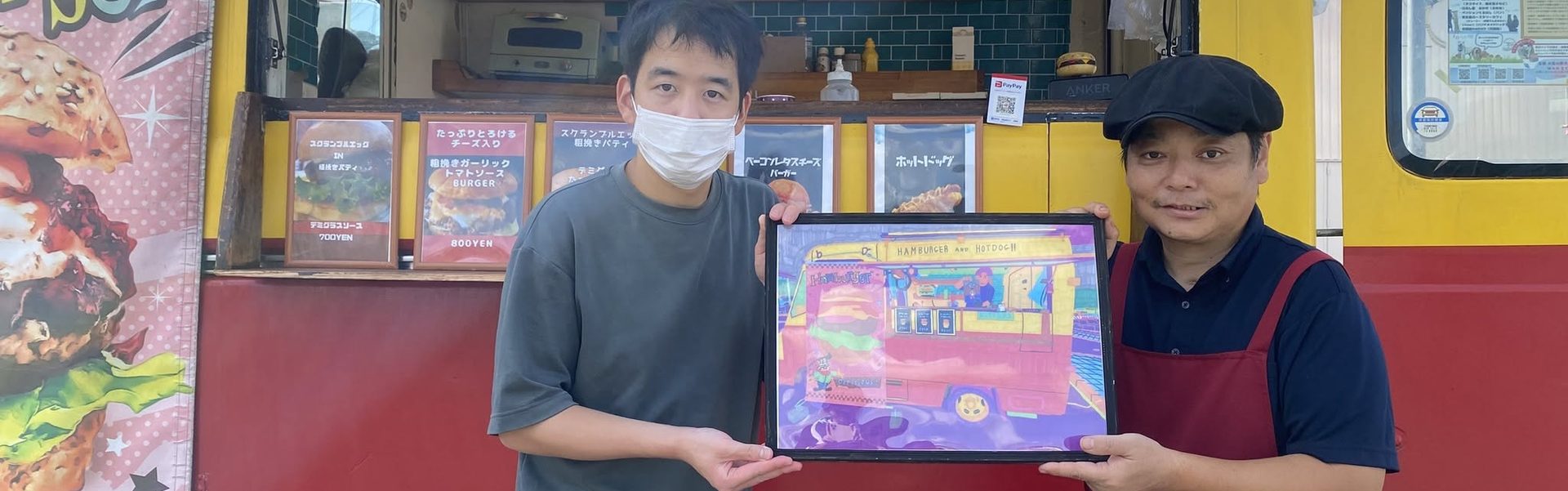 キッチンカーの前で作品を持つスタッフ